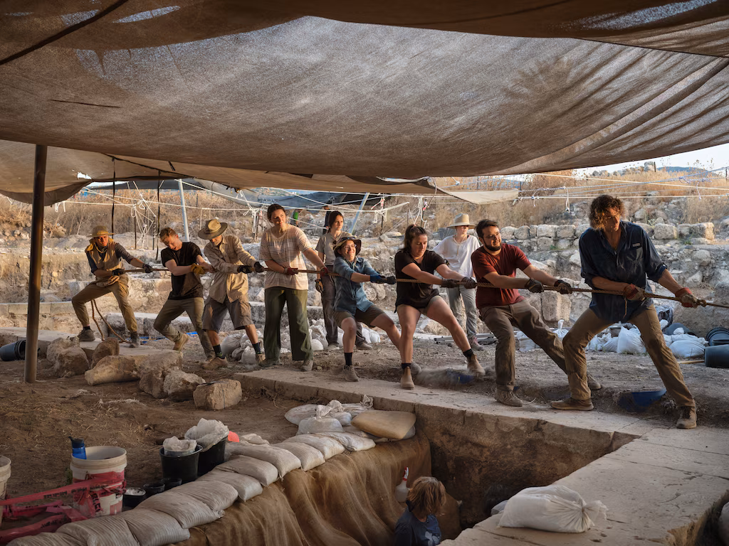 אנשי הצוות מתייצבים יחד כדי למשוך אבן כבדה מאזור החפירה